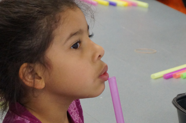 Blow across the top of the straw.